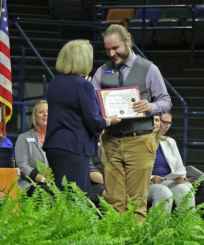 ESL Coordinator John Barnett receives a Gold Star Teacher Award from Wallace State President Dr. Vicki Karolewics during the 2024 Adult Education Graduation.