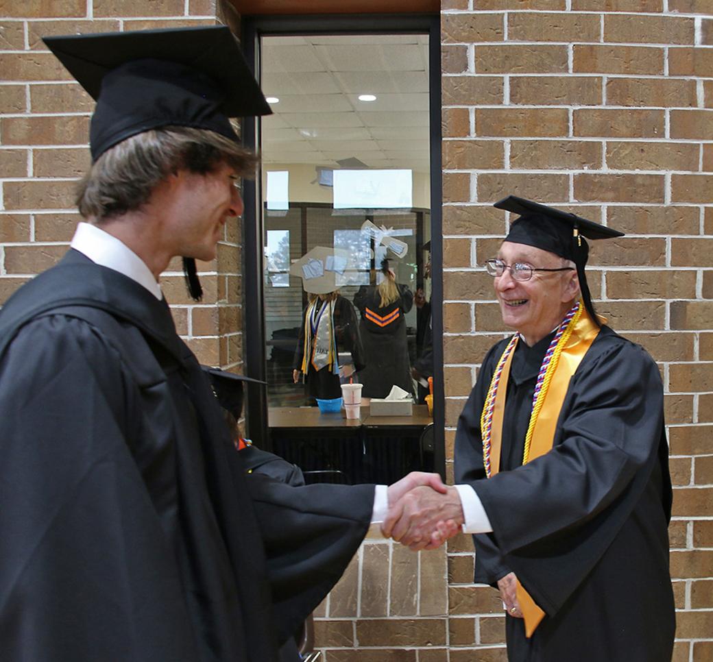 George Brady shakes hands with classmate at 2024 graduation ceremony